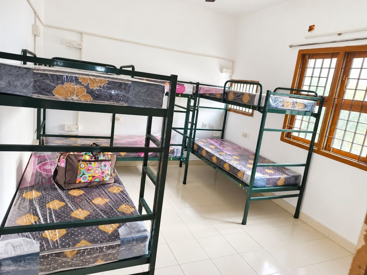 Bunk beds with mattresses in a bright tiled shared room with a window